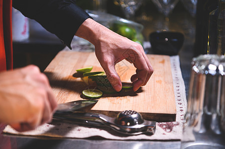 在夜总会用刀制作柠檬水汁的专业调酒师手切柠檬的特写镜头 厨师在酒吧餐厅为客人制作饮料 食品和饮料的概念美食木板甜点男人厨房桌子食图片