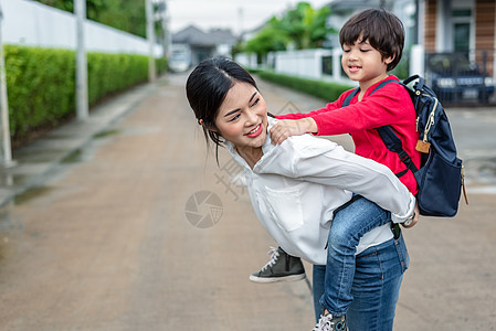 单亲妈妈带着她的孩子在家附近玩耍 有别墅街道背景 人与生活方式的概念 幸福的家庭和家庭甜蜜的家庭主题 户外和自然主题儿子小猪女士图片