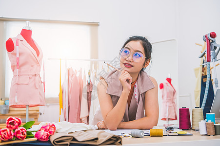 在家庭办公室车间工作的迷人亚洲女性时装设计师 时尚的时尚达人女性创造新的布料设计系列 裁缝和缝纫 人们的生活方式和职业概念手工作图片