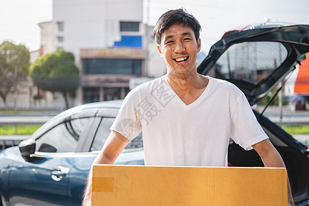 快乐的亚洲男人正在通过私家车向顾客运送纸箱 人们的生活方式和商业职业概念 穿便服的年轻男快递员图片