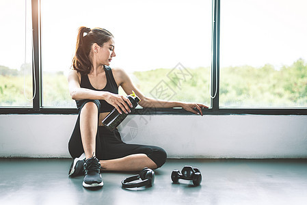 有哑铃和设备锻炼生活方式锻炼的女性在健身房健身打破放松后运动训练与蛋白质奶昔瓶背景 健康的生活方式健美和运动员肌肉瓶子运动装俱乐图片