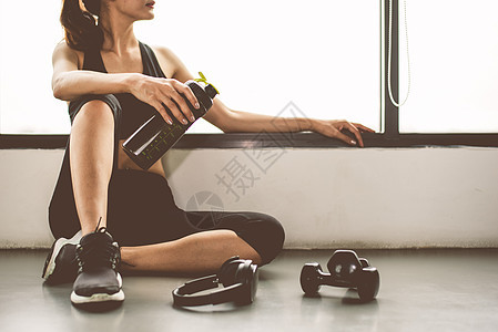 有哑铃和设备锻炼生活方式锻炼的女性在健身房健身打破放松后运动训练与蛋白质奶昔瓶背景 健康的生活方式健美和运动员肌肉培训师灵活性饮图片