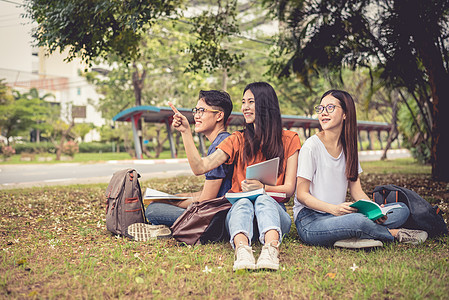 一群亚洲大学生在户外草地上阅读书籍和辅导特殊课程 幸福与教育学习理念 回到学校的概念 青少年和人的主题男人团体朋友们药片女孩女性图片