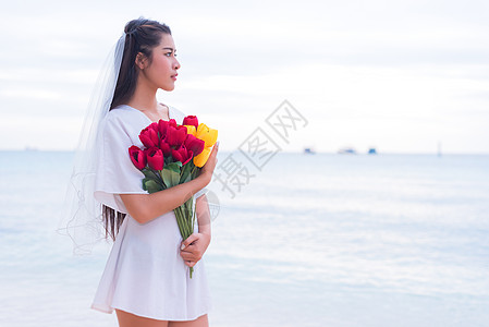 亚洲女人手捧鲜花等待某人让她开心 孤独和单身女人的概念 悲伤和命运的概念 美丽与自然主题 海洋和海洋主题 寻找灵魂伴侣主题图片