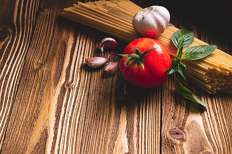 美味可口的意大利面条面食配料 用于厨房烹饪 在木制棕色桌子上放有番茄 大蒜和罗勒 食品膳食和意大利食谱自制 上面的顶视图餐厅美食图片
