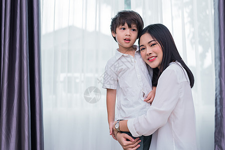 美丽的亚洲女人拥抱并带着她的儿子 幸福的家庭和家庭甜蜜的家概念 爱与生活方式的主题图片