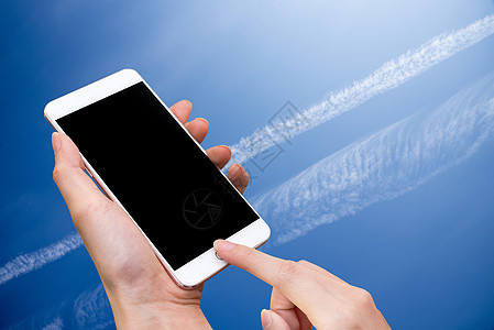 女性手持智能手机和触摸按钮 空白屏幕用于广告 蓝天和抽象背景 技术和自然概念图片
