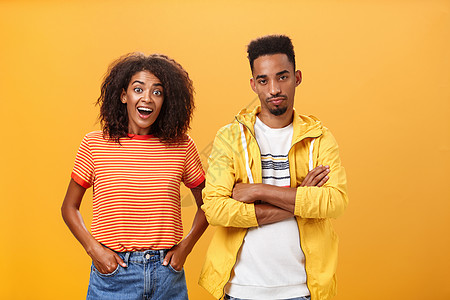 两个非洲裔美国朋友站在橙色背景下 女孩认为这个想法很棒 感到兴奋和快乐 而男朋友则对平淡的计划感到不满和漠不关心女性爆炸头发发型图片