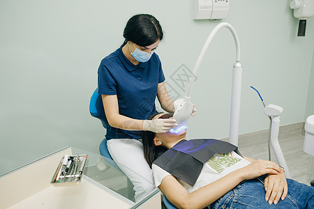 牙齿美白程序 牙医口腔科医生在带灯的医学牙科诊所为病人美白牙齿 牙齿护理和牙科的概念图片