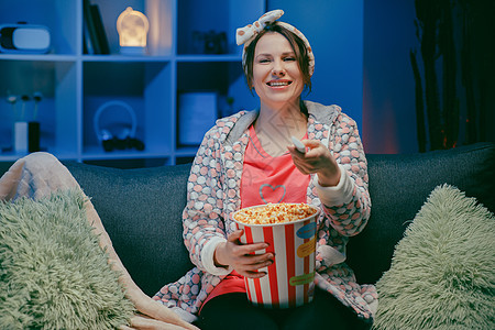 快乐的休闲女性 脸上滑稽 吃着爆米花 坐在沙发上看电影 享受真诚的积极情绪 用笑声尖叫图片