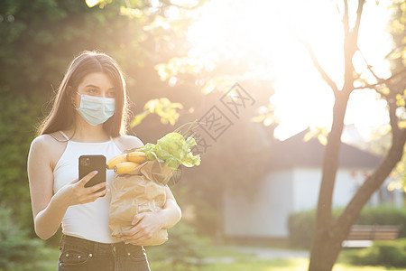 妇女在检疫期间戴口罩预防冠状病毒 送外卖 使用手机的女人图片