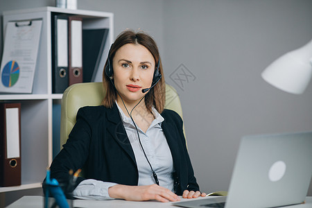 戴着耳机的女性拿着纸质财务报告在网络摄像头谈话时在办公室进行视频通话 商务教练看着镜头说话显示统计数据为客户解释营销策略内阁女士图片