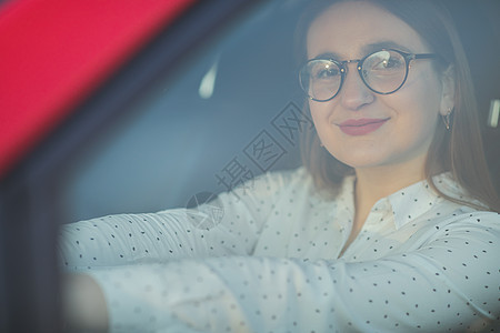 穿着眼镜的女孩从车窗走过 漂亮的女孩坐在一辆红色的新车上 她看起来很帅气的 (笑声)图片