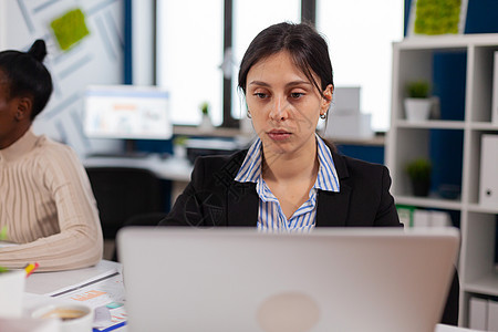 集中的经理打字 在笔记本电脑上 坐在办公启动办公室的书桌图片