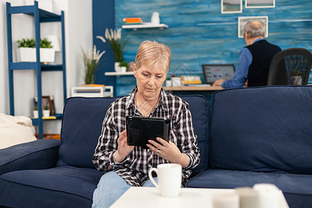 中年女士在沙发上放松 在平板电脑上阅读图片