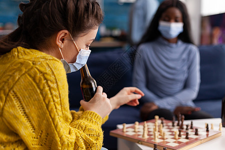 拿着啤酒瓶玩象棋的开心女人图片