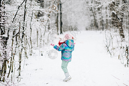 冬天在雪地里玩耍的小女孩进入室外公园 孩子用冷杉树抖掉积雪 冬季幸福概念 下雪的天气图片