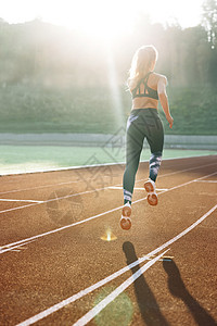 夏季晨光下在田径场上跑步的女运动员后视图 合适的女人在训练期间在跑道上跑步 在田径赛道上练习的女赛跑者 女运动员图片