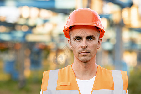 身穿安全背心 戴上安全帽的年轻专业重工业工程师工人的画像 在背景未聚焦的大型发电站图片