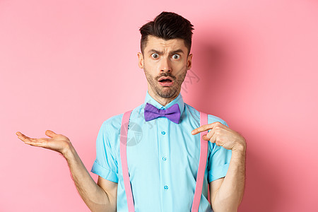 惊吓和困惑的家伙指着自己 不相信 被控告 站在粉红色背景上 在领带和吊带中站立领结成人办公室成功情绪工作室促销吊带裤胡须广告图片