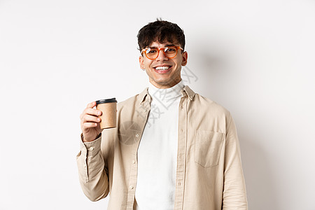 真实的人 快乐的年轻人用纸杯喝咖啡 在最喜欢的咖啡馆点外卖 微笑着看着相机 白色背景饮料潮人情绪生活男人成人商业成功促销发型图片