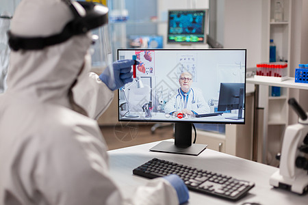 通过视频电话监听专业医生的录像电话 在Pee suit中进行切化师专家技术工作服个人同事团队实验室医师治疗化学家图片