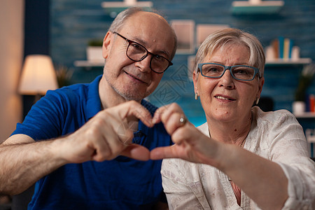 退休男女心形手牵手的肖像 其特征如下感情妻子幸福丈夫微笑手势家庭周年成人女士图片