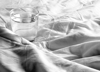 铺在床上的毯子上的玻璃杯水床单白色棉布休息玻璃卧室酒店房间图片