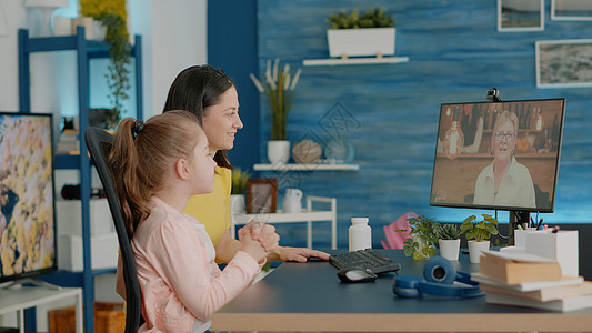 母亲和女儿用视频电话与祖母聊天 使用视频电话技术孩子们亲戚们父母妈妈女孩电脑互联网幸福社交图片