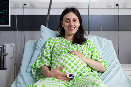 怀着微笑和握手在肚子上怀孕的妇女的肖像分娩病人劳动产科母性医疗母亲宫缩产妇技术图片
