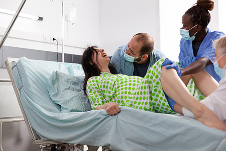 年轻妇女分娩和被推入医院病房的床位丈夫父母房间婴儿保健孩子护士送货劳动母性图片