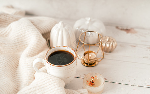 静物的细节 一杯茶或咖啡 南瓜 蜡烛 白桌背景上带叶子的早午餐 舒适房子里的家居装饰 秋季周末的概念 落叶和家居装饰饮料烛光卡片图片