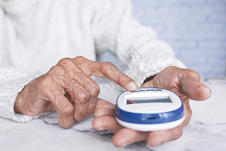 家中高龄妇女在家里的糖尿病测量葡萄糖水平诊所电子治疗控制手指考试病人测试老年图片