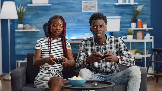 POV 黑夫妇与控制器玩电子游戏电视微笑女士男朋友游戏长椅客厅沙发家庭互联网图片