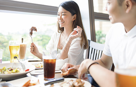 在餐厅吃午饭时玩得开心的情侣饭馆男性女朋友享受微笑杯子乐趣午餐牛肉女性图片