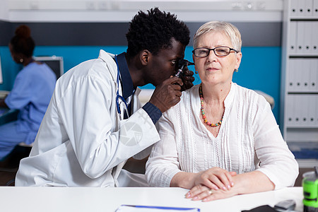 黑人青年医生对老年病人使用眼透镜男人成人工作女士咨询耳朵考试耳科测量临床图片