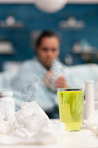 冷酷的年轻女人坐在沙发上坐在家里 喝着一杯茶药品卫生毯子头痛发烧治疗温度温度计流感保健图片