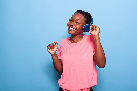 独自在有蓝背景的演播室跳舞的非裔美国青少年肖像图片