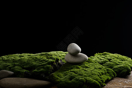 绿色苔藓上的圆形石头堆 黑色背景 展示产品 化妆品和物品 广告的讲台图片