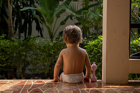 一位迷人的幼儿坐在阳光下的房子的楼梯上 背影男生享受人体孩子童年摄影幸福快乐情绪晴天图片