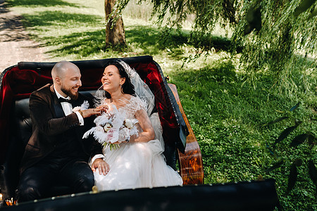 带花束的新娘和新郎正坐在一辆马车里 自然而然地穿旧风格戏服新婚丈夫领结幸福夫妻裙子已婚婚礼妻子图片