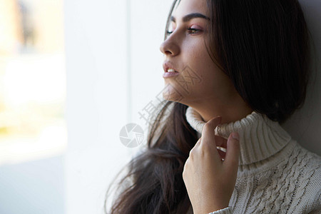 穿白毛衣的黑发美女向窗外看沮丧疼痛窗户头痛悲伤女性情感成人孤独头发图片