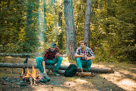 暑假森林 春天在大自然中野餐的好日子 春季或秋季露营 朋友们徒步旅行者在营地里一起看火 快乐的年轻男性朋友去野餐图片