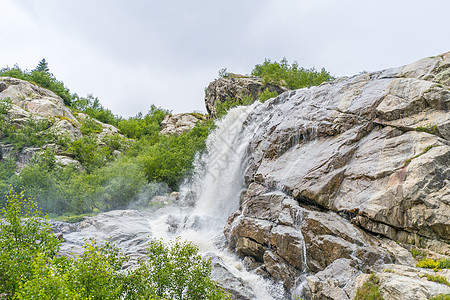 自然的夏季降水日 在乡村阳光明媚的夏日 从岩石向蓝天倾盆而来的快速水流地形季节环境天空流动溪流海岸农村力量活力图片