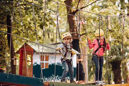 绳索公园 - 攀岩中心 无忧无虑的童年 快乐的小女孩和男孩爬树 冒险攀登高线公园 徒步旅行和孩子们的概念图片