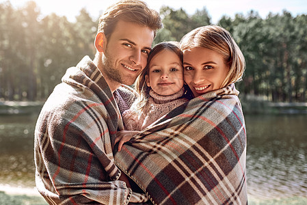 年轻父母拥抱自己的小女儿 在湖边的秋天森林里闲暇男人女孩季节童年喜悦微笑男性成人婴儿图片