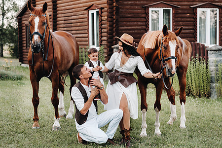 白衣家庭与儿子一起站在两匹美丽的自然马旁 一对有孩子的时装夫妇被用马拍下照片 a 一名男子牛仔妈妈家史牧场闲暇日落男人男生娱乐动图片