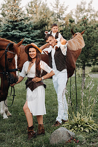 白衣家庭与儿子一起站在两匹美丽的自然马旁 一对有孩子的时装夫妇被用马拍下照片 a 一名男子自由男生动物牛仔农场孩子们衣服爸爸女士图片
