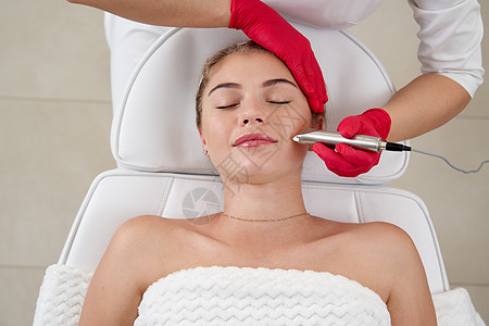 美容学家对美丽的年轻病人的脸部进行硬件清洁 其概念是皮肤净化和恢复弹性能力 a 设计机器美容师洗涤器去角质打扫毛孔粉刺仪器程序女图片