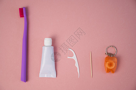 粉红色背景的个人口腔卫生产品 牙刷管牙膏牙签和牙线 平面图片